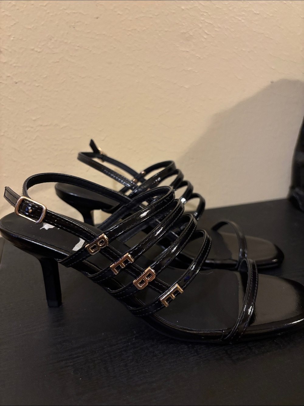 bebe Black Patent Strappy Heels with Gold Logo Accents